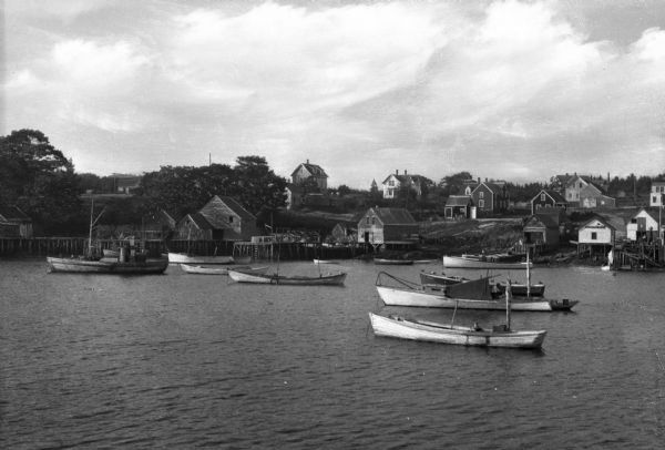 Boats in the harbor and fishermens' shanties along the far shoreline.