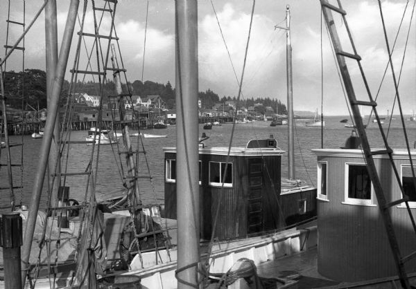 A view across two fishing boats toward others moored in the harbor.