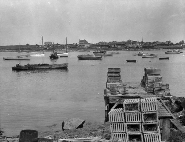 A view of a wharf with lobster pots and boats in the harbor.