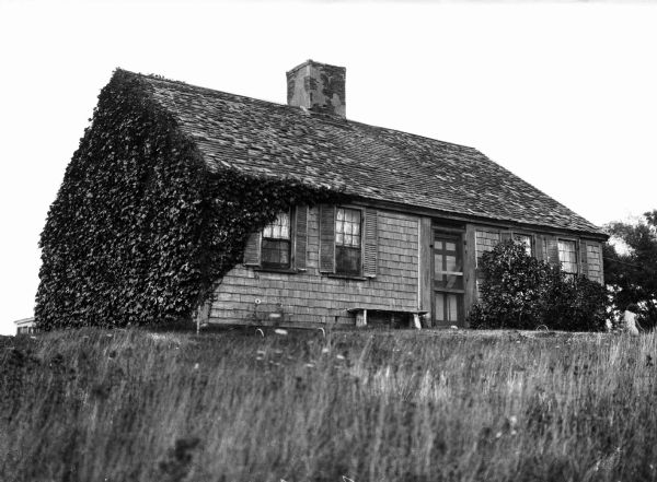 A view of an ivy-covered cottage with a chimney in Cape Cod.