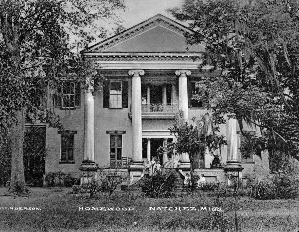 "Homewood," with its four Ionic columns in front, was built in 1855-1860 and owned by David Hunt. People are posing on the stairs at the entrance. Caption reads: "Homewood, Natchez, Miss."  