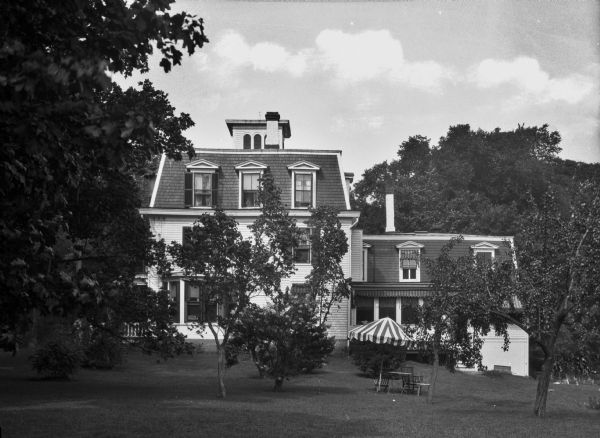 The guest house of Cora Brown, the first African American woman elected to a U.S. State Senate, with a table, chairs, and umbrella outside on the lawn.