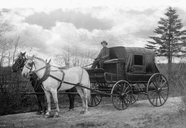 A man poses on the Continental Cove Express, a stagecoach pulled by two horses.