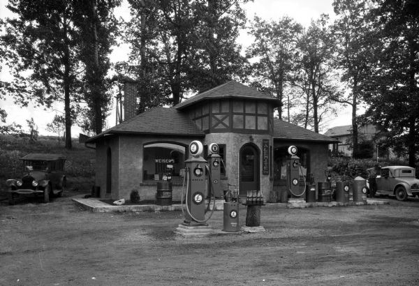 A man leaning on an automobile can be seen in the background on the right of Weiser's Service Station.