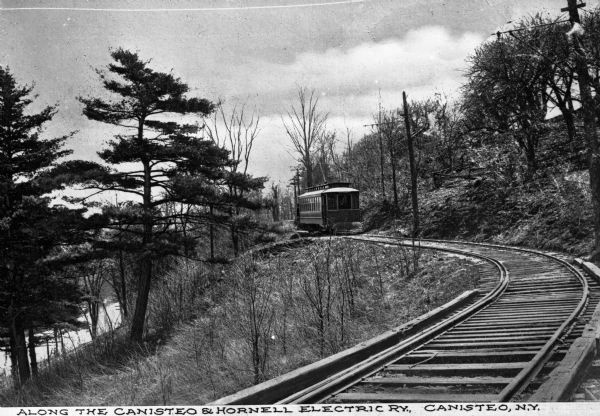View down curving tracks toward the Canisteo and Hornell Electric Railway Car, outside the city of Canisteo. Caption reads: "Along the Canisteo & Hornell Electric, Ry., Canisteo, N.Y."
