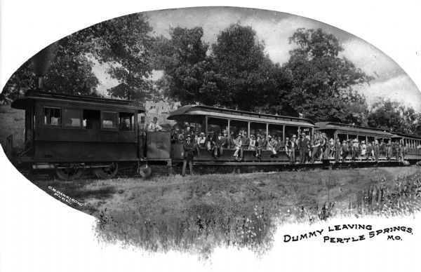 View toward a large group of people posing on railroad cars and the locomotive  on tracks. Caption reads: "Dummy Leaving Pertle Springs, MO." A man holding a dummy can be seen in the second window section of the first passenger car.