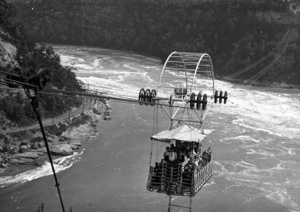 Designed by Leonardo Torres y Quevedo and built in 1913. Elevated view looking down at people in the Whirlpool Aero Car which is crossing the 60-acre whirlpool of Niagara Falls.