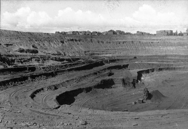 A view of the Susquehanna Open Pit Iron Ore Mine, with a residential area of Hibbing, Minnesota in the distance.