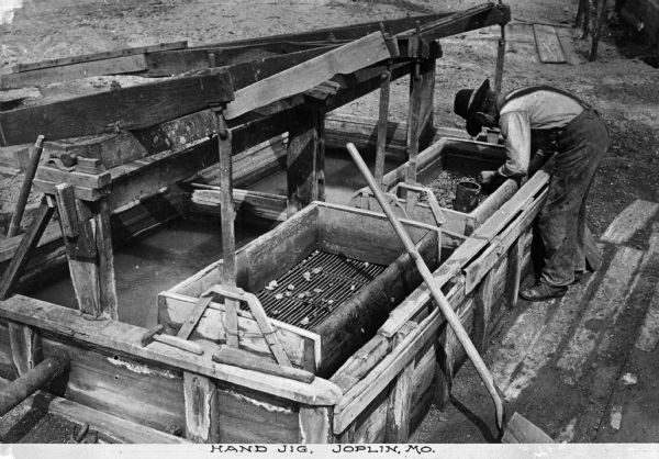 Soon after the turn of the century, Joplin was named the lead and zinc capital of the world. Elevated view of a man working with a hand jig. Caption reads: "Hand Jig, Joplin, MO."