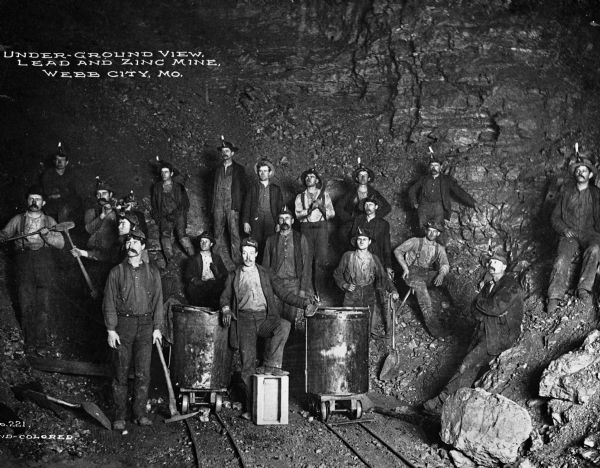 Webb City was known as the world's largest and most productive lead and zinc mining field in the late 1800s and early 1900s and was part of the "Tri-State Mining District." An underground view is shown of the mine with a group of workers. Caption reads: "Under-ground View, Lead and Zinc Mine, Webb City, MO."
