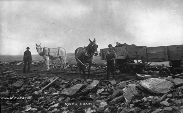 Mules and wagons can be seen with men on a rock bank while mining. Caption reads: "Rock Bank."