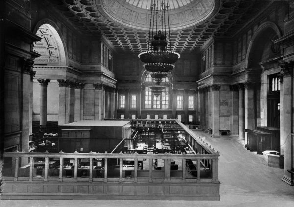 Corinthian columns, a high coffered ceiling, a skylight, and a chandelier adorn the lavish interior of the National City Bank of New York. The bank was built in the Greek Revival style between 1836 and 1841.