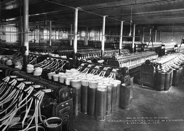 An interior view of large machines in the card room of Massachusetts Mill, which produced 1/7 of all textiles in Georgia. Caption reads: "No. 2 Card Room, Massachusetts Mills in Georgia, Lindale, GA."
