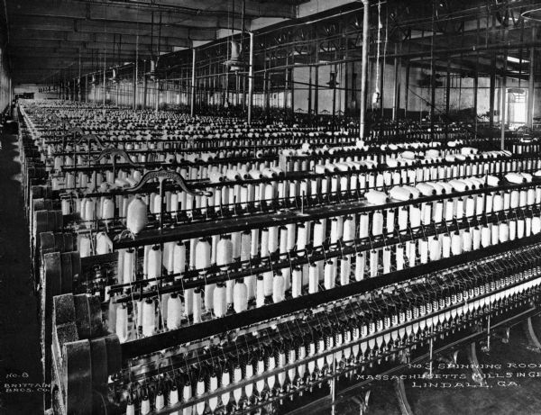 Rows of large spinning machines can be seen in the card room of Massachusetts Mill, which produced 1/7 of all textiles in Georgia. Caption reads: "No. 3 Spinning Room, Massachusetts Mills in Georgia, Lindale, GA."