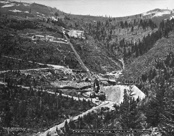 An elevated view of the Hercules Mine in a mountain setting.  Mining operations began in Hercules Mine in 1889. Caption reads: "Hercules Mine — Wallace, Idaho."