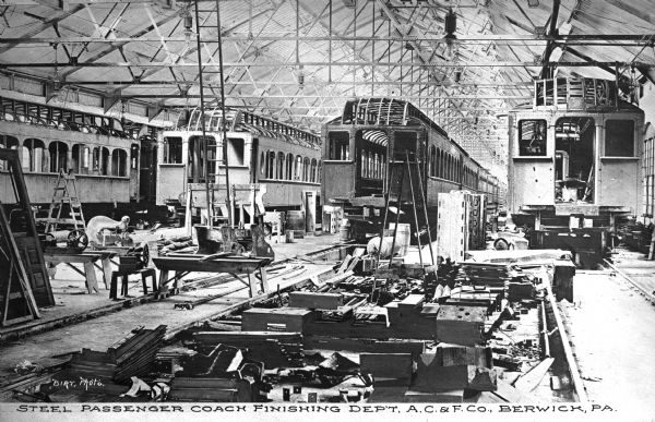 The former Berwick company, Jackson and Woodin Manufacturing Company, was founded in 1861 and became part of the American Car and Foundry Company in the 1899 merger.  Men are shown at work in the steel passenger coach finishing department.