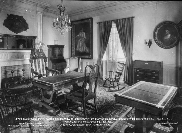 A general view of the President General's Room in Memorial Continental Hall. Tables and chairs lie in the foreground on a decorative rug with a fireplace and window behind them. Portraits and other decorative objects line the walls. Caption reads: "President General's Room — Memorial Continental Hall, Washington, D.C. Furnished by Indiana."
