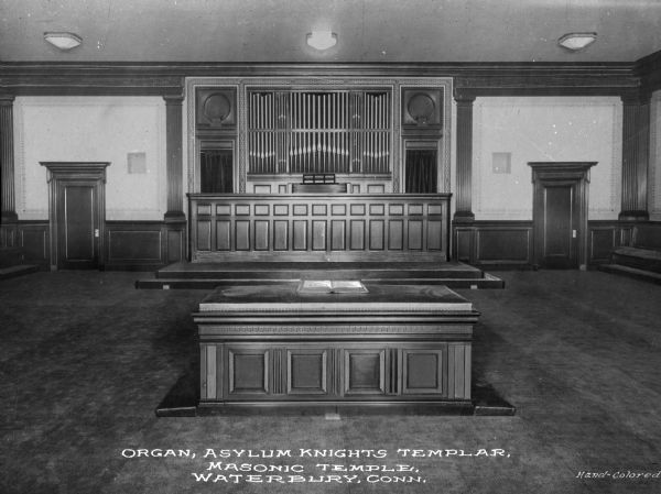 A view of an altar and an organ in a Masonic Temple of the Asylum Knights Templar, an international philanthropic chivalric order affiliated with Freemasonry. Caption reads: "Organ, Asylum Knights Templer, Masonic Temple, Waterbury, Conn."