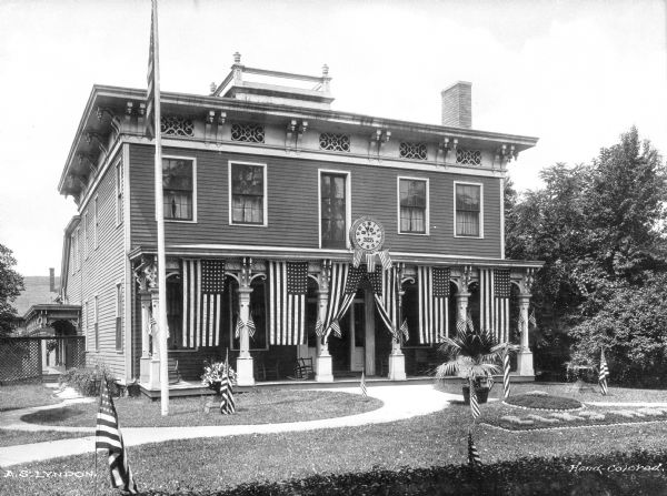 Front view of the exterior of the Elks Home. Flags adorn the home and lawn.