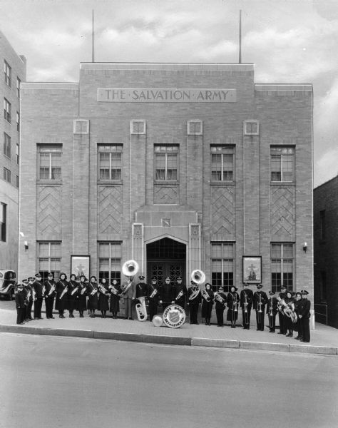 Front view of the Salvation Army home. The band is assembled in front of the home, holding instruments.