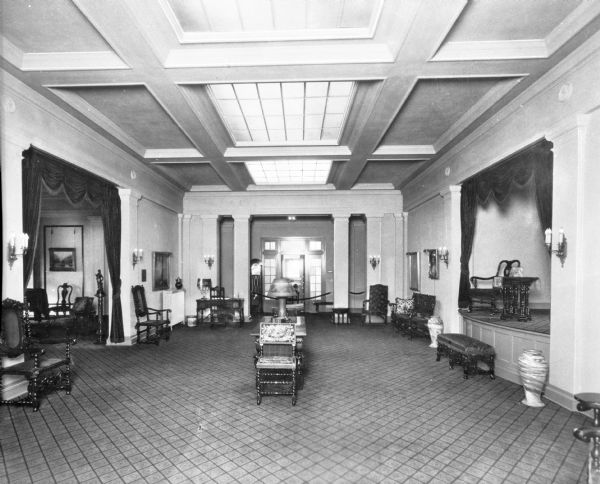 Interior view showing the stage and reception hall of the Philanthropic Educational Organization, founded in 1869.  Decorative seating, tables, draperies, and vases are shown in the hall.