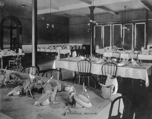 A view of dishes on the dining room tables in Pythian Orphans' Home. Caption reads: "Dining Room."
