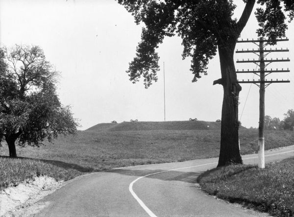 A road curves to the right and in the background is the Star Redoubt, a military structure built by Continental soldiers during the winter encampment of 1777-1778. A telephone pole is on the right.