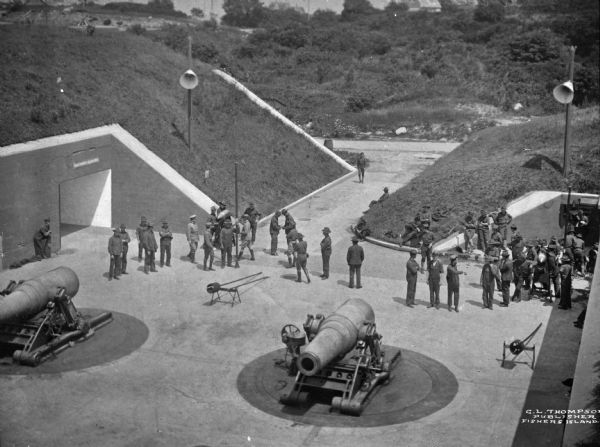 Elevated view of a group of men standing by large guns.