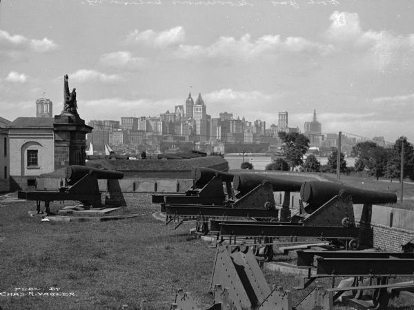 A view of artillery and guns at Fort Jay, built in 1794 to defend Upper New York Bay. The New York cityscape is across the bay.