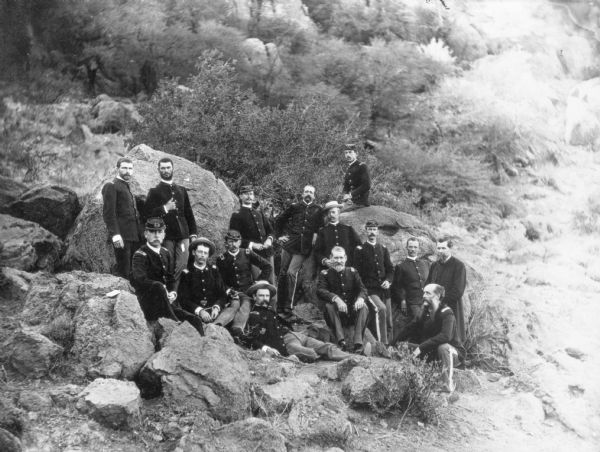 View looking down toward a group of officers sitting and standing together among large rocks.