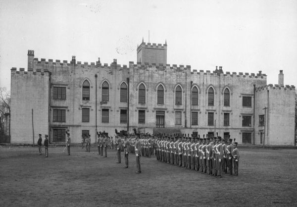 Soldiers marching in formation in front of a large building at the Military Academy.