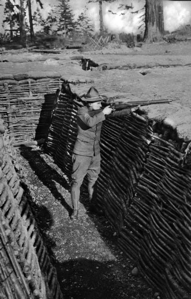 A man demonstrating trench shooting in a fortified ditch at Camp Lewis, built in 1917.