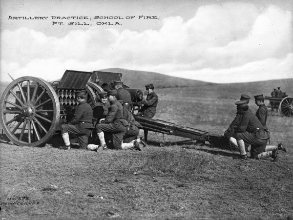 A view of soldiers in an open field during artillery practice at The School of Fire, founded in 1911 at Fort Sill. Caption reads: "Artillery Practice, School of Fire, Ft. Sill, OKLA."