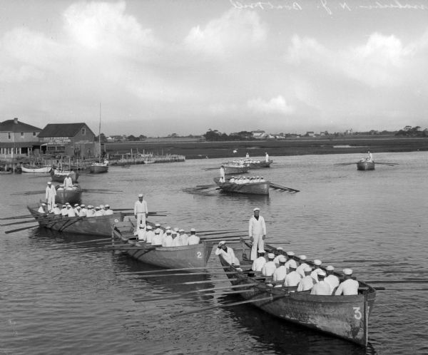 A view of sailors rowing ten boats toward the shore during a drill at the United States Navy Camp Wissahickon.