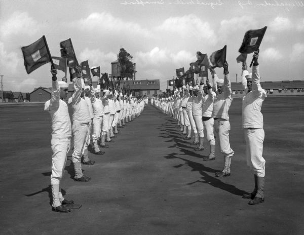 Two rows of sailors hold flags during a semaphore drill at the United States Navy Camp Wissahickon.
