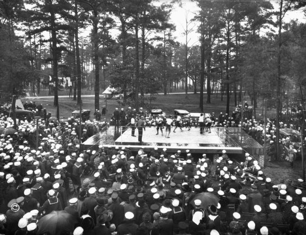 A view of sailors seated around a boxing ring, watching a match at a United States Naval Training Camp.
