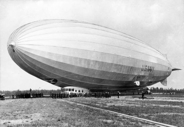 A view of "Los Angeles," completed in 1924, at the Naval Air Station.  The airship has landed in a field and is loading passengers.