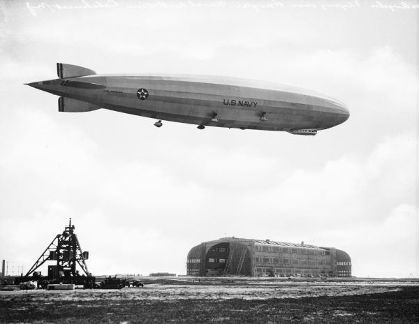 The "Los Angeles," completed in 1924, can be seen flying over Hangar No. One, a steel structure erected in 1920, at the Naval Air Station.