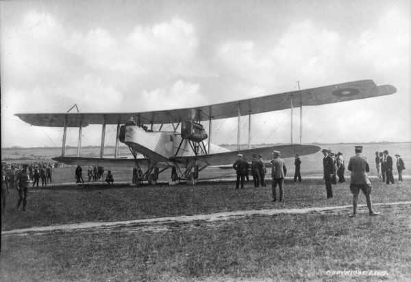 Men observe an early airplane at Camp Bowie, established in 1917.