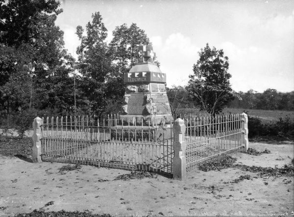 View of a monument on a battlefield to Major General John Sedgwick, killed in action on May 9, 1864. The memorial, erected in 1887 by veterans of Segdwick's Corps, stands surrounded by a fence at the place of his death.