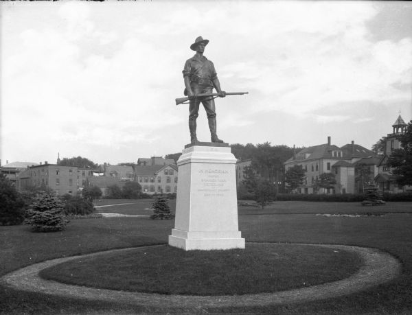 View of a copy of "The Hiker," a Spanish War Memorial found in Deering's Oak Park, originally designed in 1906 by Theo Alice Ruggles Kitson. Residences and other buildings are behind the monument.