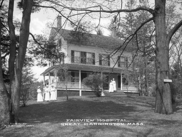 A view toward the Fairview Hospital, which opened in 1913. Nurses pose in front of the residential-looking building surrounded by a lawn and trees. Caption reads: "Fairview Hospital, Great Barrington, Mass."