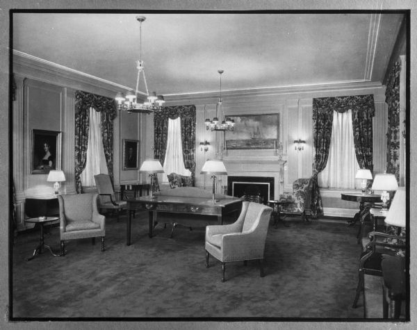 Interior of the main lounge of the Doctor's Hospital, founded by Theodore Atlas in the early 1900's.  The view from across the room shows furniture, tables, and a fireplace.  Paintings are framed on the wall and draperies decorate the windows.