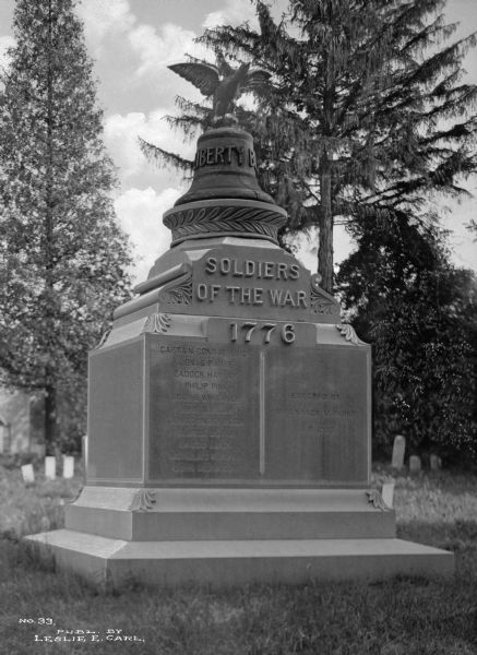 View of a Revolutionary War Memorial, erected by Mrs. Nancy M. Parke in 1903. A liberty bell and eagle sit atop a list of soldiers of the war in 1776.
