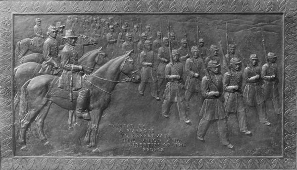 View of a bas-relief sculpture of Civil War Union troops on revue. The sculpture features men marching with firearms and men on horses. The inscription on the sculpture reads, "United by a purpose to perpetuate the Union and liberties of the people."
