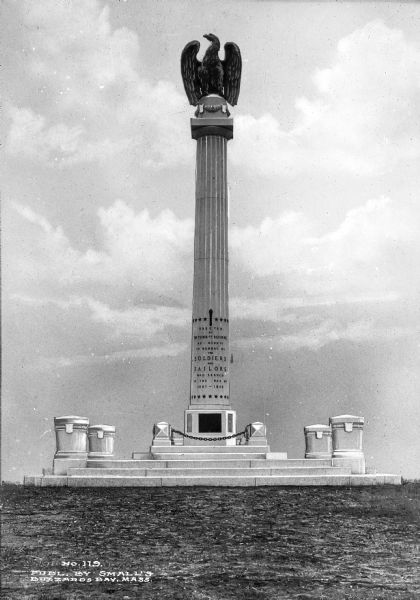 View of a Civil War Monument on Cape Cod Canal, erected by the town of Bourne in 1914. The text reads, "In memory of the soldiers and sailors who served in the war of 1861 - 1865." Atop the monument sits an eagle.