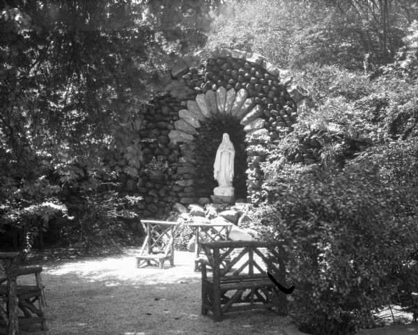 View of a grotto at the College of the Sacred Heart, founded in 1841. A Madonna statue stands in a niche in the grotto, and kneelers can be seen before the statue.