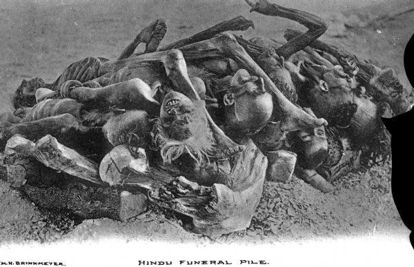 View of a funeral pyre for a group of deceased Hindu people. Remnants of bodies lie on a stack of logs for cremation. Caption reads: "Hindu Funeral Pile."