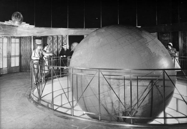 Observers stand around a circular railing looking at a large, rotating globe in the Daily News Building, constructed in 1930.