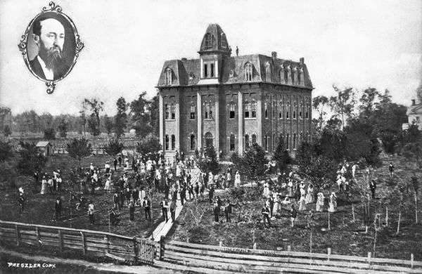 Elevated view of the Northwestern Ohio Normal School, founded in 1871 by Henry Solomon Lehr. Groups of people pose on the school's lawn, and two men stand on the rooftop. At top left is an oval-framed portrait of a man.